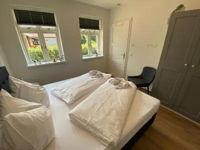 Ein Bett oder Betten in einem Zimmer der Unterkunft Friesia Urlaub unterm Reetdach fuer 4 Pers Terrasse Garten 2 SZ